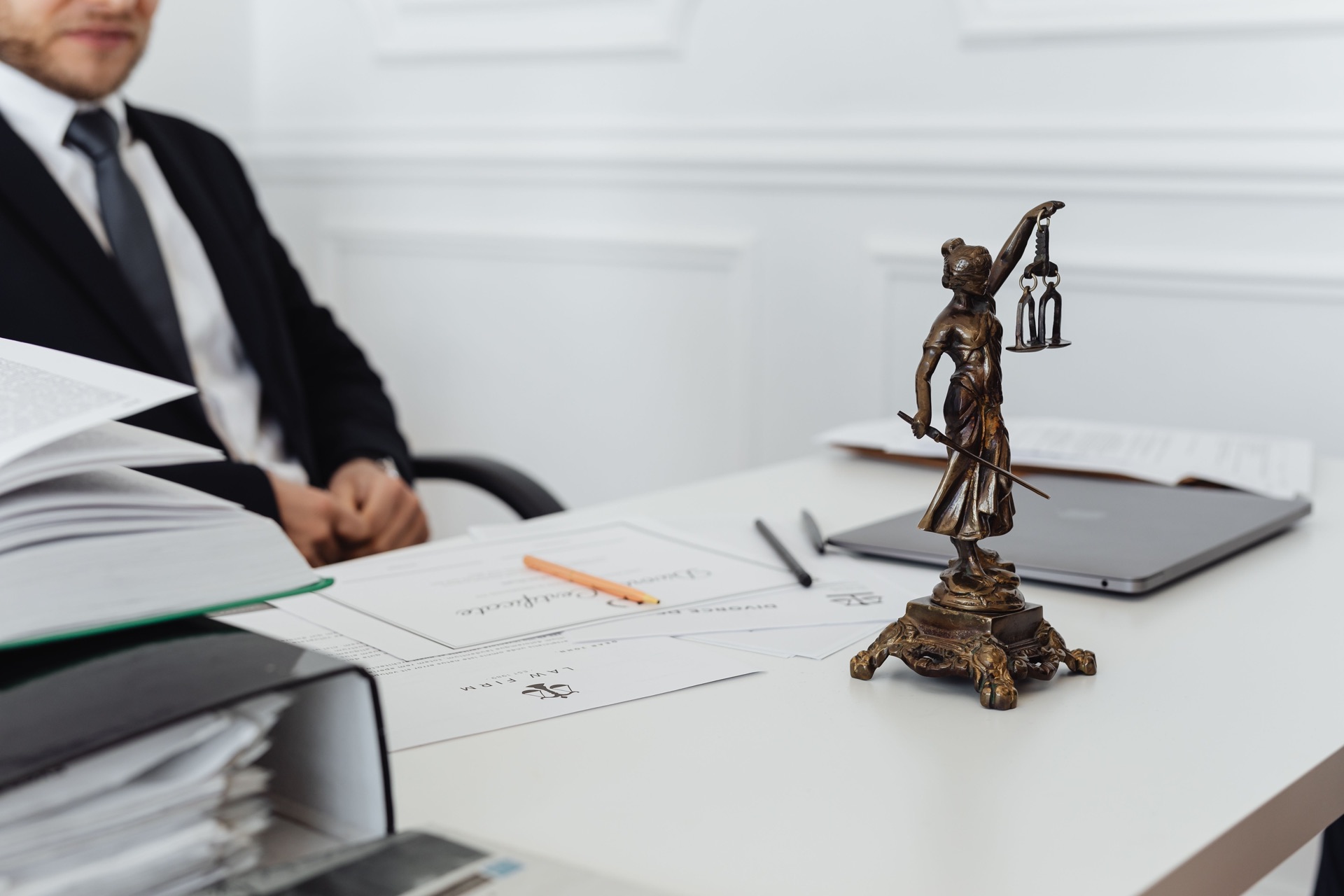 An attorney's desk with a scales-of-justice statue and legal documents